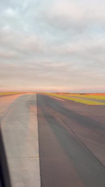 Gün doğumunda pistte hızla ilerleyen bir uçak, gökyüzünün ve manzaranın canlı renklerini yakalıyor.