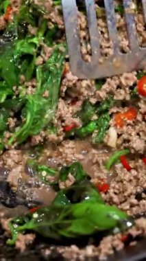 Canlı renklerde ve hareketli bir tavada kızartılmış biftek, fesleğen ve biber yakın plan.