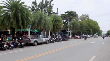 Motosikletler ve arabalar hareketli bir caddede yol alırlar.