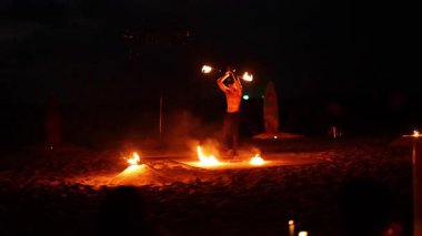 Karon Sahili, Phuket 'te büyüleyici bir yangın gösterisi. Karanlık, atmosferik bir arka plana karşı becerikli bir ateş manipülasyonu.