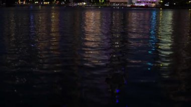 Şehir ışıkları geceleri suyu yansıtıyor.