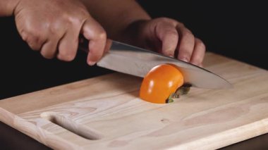 Hands skillfully cutting a ripe persimmon