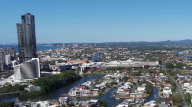 Gökdelenleri, yerleşim alanları ve açık mavi gökyüzünün altındaki su yolları olan bir şehir manzarası.