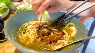 Bir el, bir kase Vietnam piposunun üzerine limon sıkıp, canlı tadını arttırıyor. Parlak ışıklandırma taze malzemelerin altını çizer