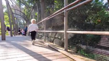 Bir çocuk hayvanat bahçesindeki kuş kafesinde yürüyor.