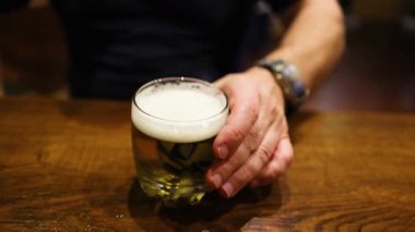 Adam ahşap masaya bira döker.