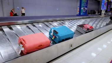 Havaalanındaki bagaj teslim yerinde bavullar taşınıyor.