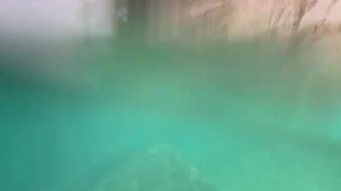 Kayalık bir kıyı şeridi yakınında sakin bir sualtı yolculuğu, Phuket, Tayland 'daki canlı turkuaz suları ve doğal kaya oluşumlarını yakalıyor.