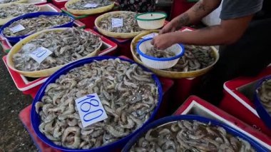 Çeşitli sepetlerden karides seçen kişi