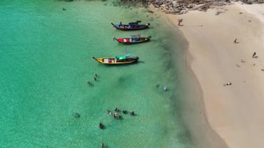 İnsansız hava aracı görüntüleri Phuket, Tayland 'daki canlı sahil yaşamını, uzun kuyruklu tekneleri, yüzücüleri ve manzaralı tropikal manzaraları görüntülüyor.