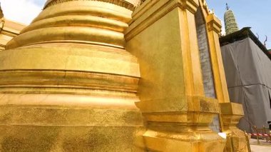 Wat Phra Kaew 'deki altın pagoda' nın dinamik bir görüntüsü, Bangkok, Tayland 'da gün ışığında karmaşık mimarisini gözler önüne seriyor.