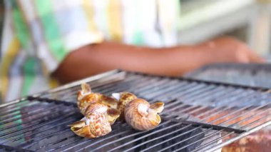 Dışarıda ızgarada salyangoz pişiren biri.