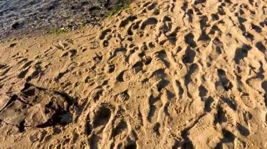 Su kenarında kumdaki ayak izleri.