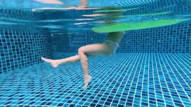 Bir havuzda iki kişi yüzüyor.