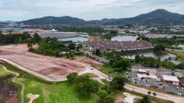 Havadan alınan görüntülerde Phuket, Tayland 'da yapım aşamasındaki bir golf sahası gösteriliyor, yemyeşil alanlar ve çevreleyen manzaralar vurgulanıyor