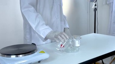 Beyaz önlüklü laboratuvar asistanı şişeleri kullanıyor.