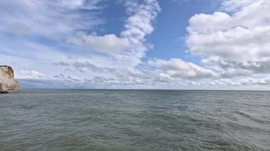 Dalgalar bulutlu bir gökyüzünün altında kayalıklara çarpıyor