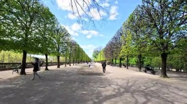 Manzaralı bir bahçede gezinen insanlar