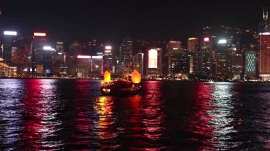 Aydınlatılmış Hong Kong limanından bir tekne geçiyor.