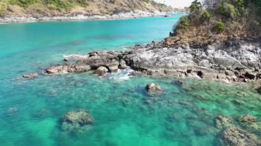 Hava görüntüleri, Phuket, Tayland 'ın sakin turkuaz sularını ve kayalık sahil şeridini gün ışığında yakalıyor.