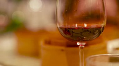 Çin restoranındaki sıcak, çevresel aydınlatma sepetlerinin arasında kırmızı şarap kadehinin yakın çekimi.