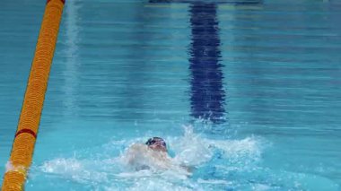 Yüzücü açık mavi havuzda pratik yapıyor.