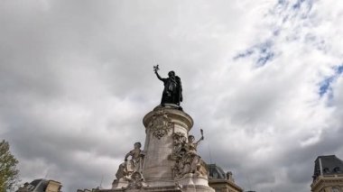 Paris 'te bir heykelin yanında yürüyen insanlar