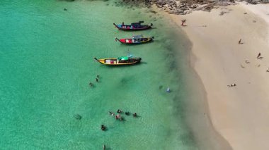 İnsansız hava aracı görüntüleri Phuket, Tayland 'daki canlı sahil yaşamını, uzun kuyruklu tekneleri, yüzücüleri ve manzaralı tropikal manzaraları görüntülüyor.
