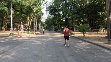 Huzurlu bir park ortamında koşan ve yürüyen kişiler