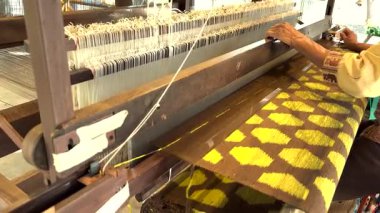 Zanaatkar elle karmaşık ipek desenler örüyor.