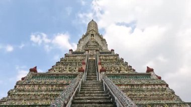 Wat Arun 'un karmaşık merdivenlerinin dinamik görüntüsü, Bangkok' ta parlak bir gökyüzü altında mimari güzelliğini sergiliyor.