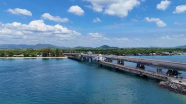 Drone görüntülerinde Phuket, Tayland 'daki Sarasin Köprüsü açık gökyüzü altında köprünün yapısını ve çevresindeki tropikal manzarayı gösteriyor.