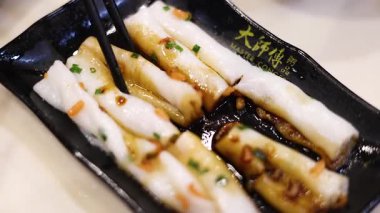 Çubuklar tabaktan pirinç eriştesi topluyor.