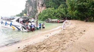 İnsanlar manzaralı bir sahilde tekneden iniyorlar.