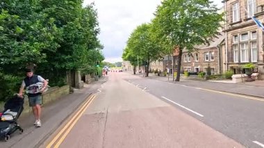 Ağaçlarla kaplı bir caddede yürüyen yayalar.