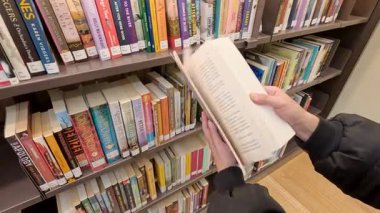 Kütüphanede bir kitabı karıştıran kişi