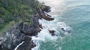 İnsansız hava aracı, Avustralya 'daki Coffs Harbour kayalıklarına çarpan dalgaları yakalıyor. Açık gökyüzü ve canlı okyanus renkleri dingin bir atmosfer yaratır.