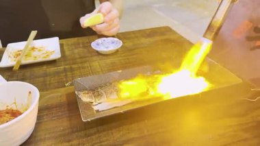 Şef balık tabağını yakmak için pürmüzü kullanıyor.