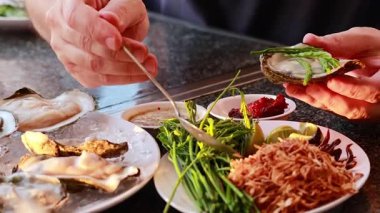 Eller çeşitli Tayland malzemeleriyle istiridye hazırlıyor.