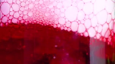 Baloncuklu canlı kırmızı bir sıvı kuru buz reaksiyona girerken oluşur ve cam bir kabın içinde dinamik bir görsel etki yaratır.