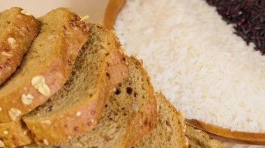 Tahta bir yüzeyde tahıl, makarna ve ekmek var. Ilık ışık altında. Yakın çekim, dokuyu ve çeşitliliği vurguluyor