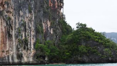 Bereketli kayalıklardan ve turkuaz denizden geçen bir tekne.