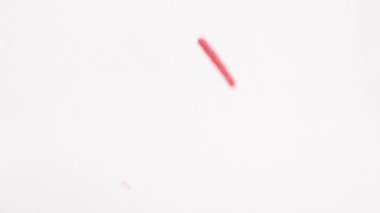 Kırmızı kalp şeklindeki şeker parçacıkları bir yüzeye dökülür ve parlak ışıkta canlı, dokulu bir yığın oluşturur.