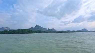 Parçalı bulutlu bir gökyüzünün altındaki uzak dağların olduğu sakin bir okyanus sahnesi, Koh Samui, Tayland 'da çekildi.