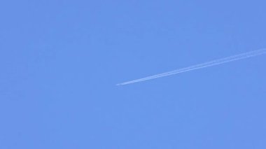Uçak açık mavi gökyüzünde iz bırakıyor