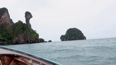 Krabi 'nin çarpıcı kıyı manzarasında yol alan bir tur teknesi.