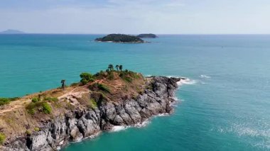 İnsansız hava aracı görüntüleri Promthep Cape, Phuket 'in çarpıcı sahil şeridini çekiyor, berrak gökyüzü altında canlı turkuaz sular ve engebeli uçurumlar sergiliyor.