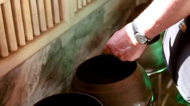 Biri Wat Pho, Bangkok 'taki sadaka kaselerine para atıyor. Huzurlu ortam yumuşak ışıklandırma ve geleneksel dekorla vurgulanır