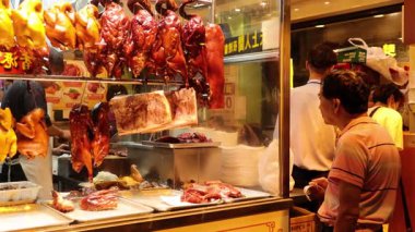 Canlı pazar sahnesi, kızarmış etler sergileniyor.