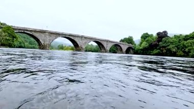 Tarihi bir taş köprünün altından akan nehir